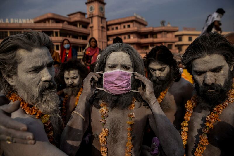This photo by Reuters photographer Danish Siddiqui, provided by Columbia University, shows a 'Naga Sadhu,' or Hindu holy man, placing a mask across his face before entering the Ganges river during the traditional Shahi Snan, at the Kumbh Mela festival in Haridwar, India, April 12, 2021.  Reuters photographers Adnan Abidi, Sanna Irshad Mattoo, Amit Dave and the late Danish Siddiqui of Reuters were awarded the 2022 Pulitzer Price for Feature Photography, Monday, May 9, 2022, for images of COVID's toll in India that balanced intimacy and devastation, while offering viewers a heightened sense of place.  (Danish Siddiqui / Reuters via AP)