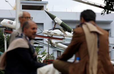 Yemenis sit in front of mock Houthi-made drones and missiles in Sanaa on November 7. Over the past five years, the rebels have shifted to small, long-range, explosive unmanned aircraft that can evade radar detection. EPA