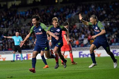 FC Salzburg's Takumi Minamino, left, celebrates with teammates after scoring his side's second goal of the game during the Europa League round of 32, 1st leg soccer match between Real Sociedad and FC Salzburg, at Anoeta stadium, in San Sebastian, northern Spain, Thursday, Feb.15, 2018. (AP Photo/Alvaro Barrientos)