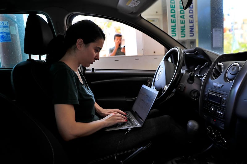 A woman in a queue for petrol in Beirut uses the time to work on her laptop. AP Photo