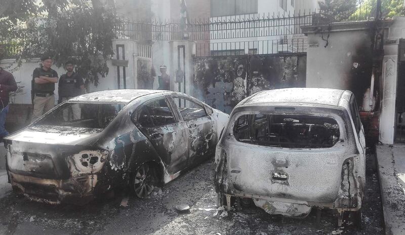 TOPSHOT - Pakistani security personnel stand next to burned out vehicles in front of the Chinese consulate after an attack in Karachi on November 23, 2018. At least two policemen were killed when unidentified gunmen stormed the Chinese consulate in the Pakistani port city of Karachi on November 23, officials said. / AFP / ASIF HASSAN
