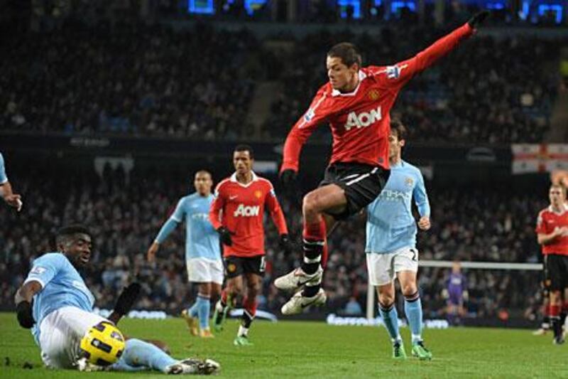 Manchester City's Kolo Toure, left, looks on as Manchester United's Javier Hernandez, right, shoots on goal.