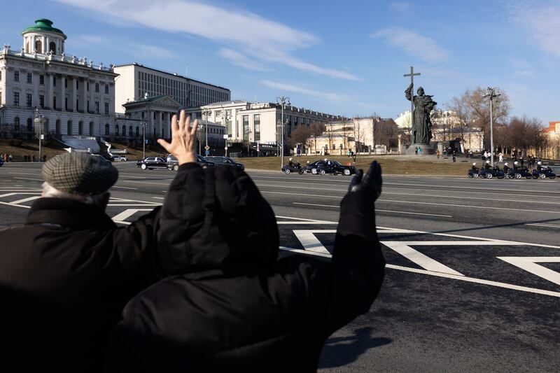 People wave at Mr Xi's motorcade driving towards the Kremlin. AP