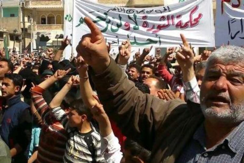 Anti-Syrian regime protesters shout slogans during a demonstration in Binish town in Idlib province on Monday. The Arabic banner in the background reads: "To who it may concern, the revolution's court will not forgive anyone".