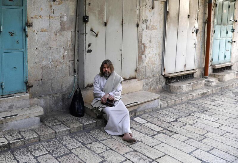 A man sits in front of closed shops in Jerusalem's Old City, amid measures to stem the spread of coronavirus, on March 27, 2020.  AFP