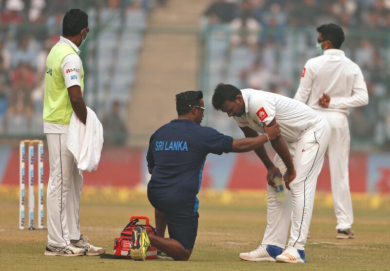 A paramedic speaks to Sri Lanka's Lahiru Gamage after he complained of short of breath during the second day of a third test cricket match against India in New Delhi. Altaf Qadri / AP Photo