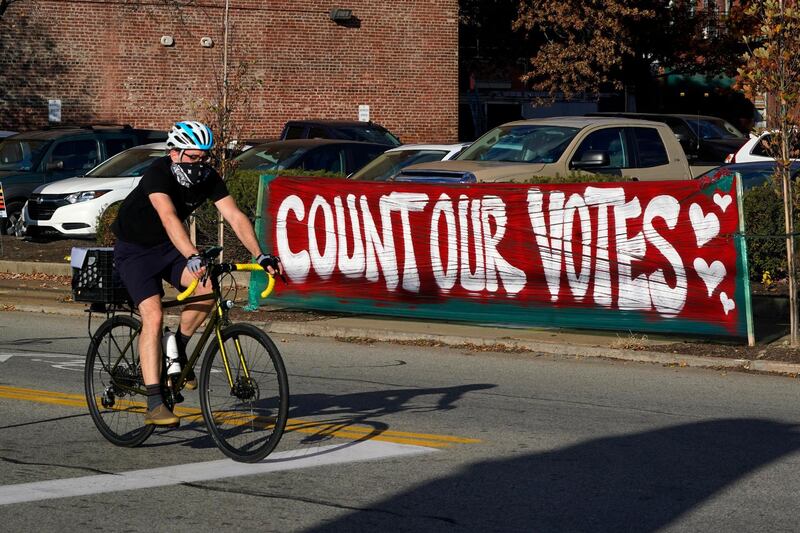 A cyclist passes a Count Our Votes sign near the Allegheny County Election Division Warehouse on Pittsburgh's Northside where votes continue to be counted. AP Photo