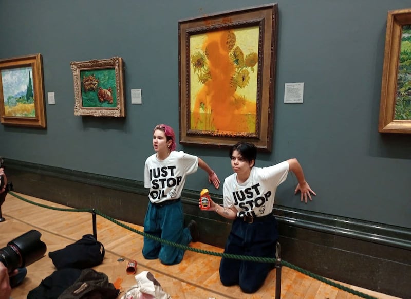 Activists from Just Stop Oil glue their hands to the wall after throwing soup at a van Gogh painting, 'Sunflowers', at the National Gallery in London. Reuters