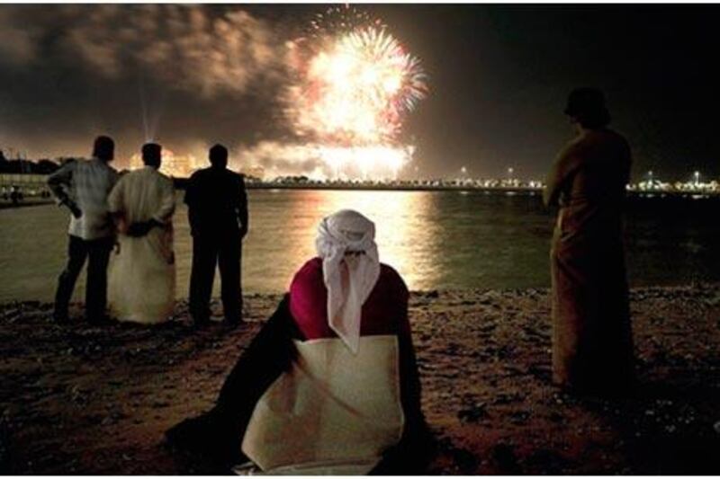 Ghader Ali Gabeer al Mansoory watches the fireworks with a flag draped over his shoulders along Abu Dhabi's Corniche.