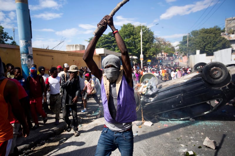 A masked man hits the ground with a stick as protesters demand the resignation of Haitian President Jovenel Moise in Port-au-Prince. AP Photo