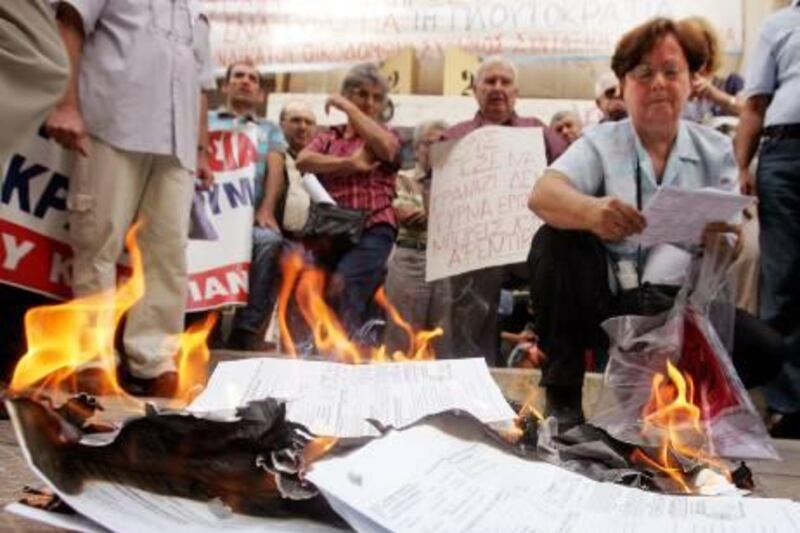 epa02941045 Members of the Greek PAME trade union, which is affiliated to the Communist Party of Greece (KKE), burn their tax bureau statements for the extraordinary surtax on real estate during a demonstration outside an Athens Tax Bureau, in Athens, Greece, on 29 September 2011. Citizens demonstrated against the government's austerity measures and plans to cut-down salaries and benefits.  EPA/ALEXANDROS VLACHOS *** Local Caption ***  02941045.jpg