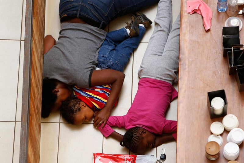 A mother and her children hide from gunmen at Westgate Shopping Centre in Nairobi September 21, 2013. Gunmen stormed the shopping mall in Nairobi on Saturday killing at least 20 people in what Kenya's government said could be a terrorist attack, and sending scores fleeing into shops, a cinema and onto the streets in search of safety. Sporadic gun shots could be heard hours after the assault started as soldiers surrounded the mall and police and soldiers combed the building, hunting down the attackers shop by shop.    REUTERS/Siegfried Modola  (KENYA - Tags: CIVIL UNREST)