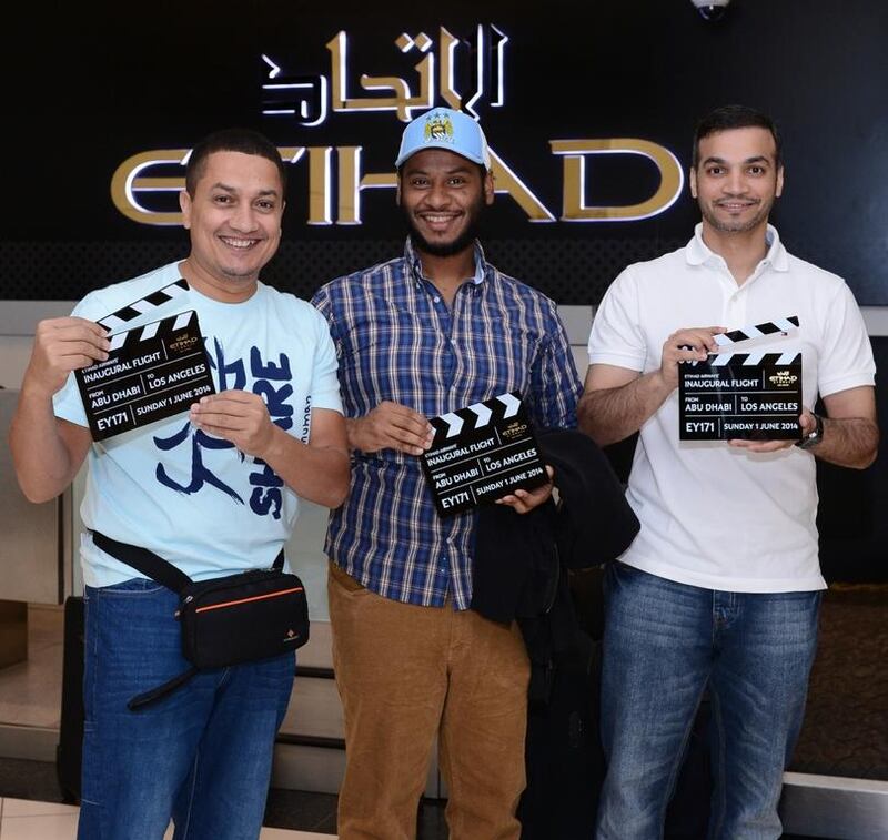 Passengers on the inaugural Etihad flight to Los Angeles show their commemorative clappers. Courtesy Etihad