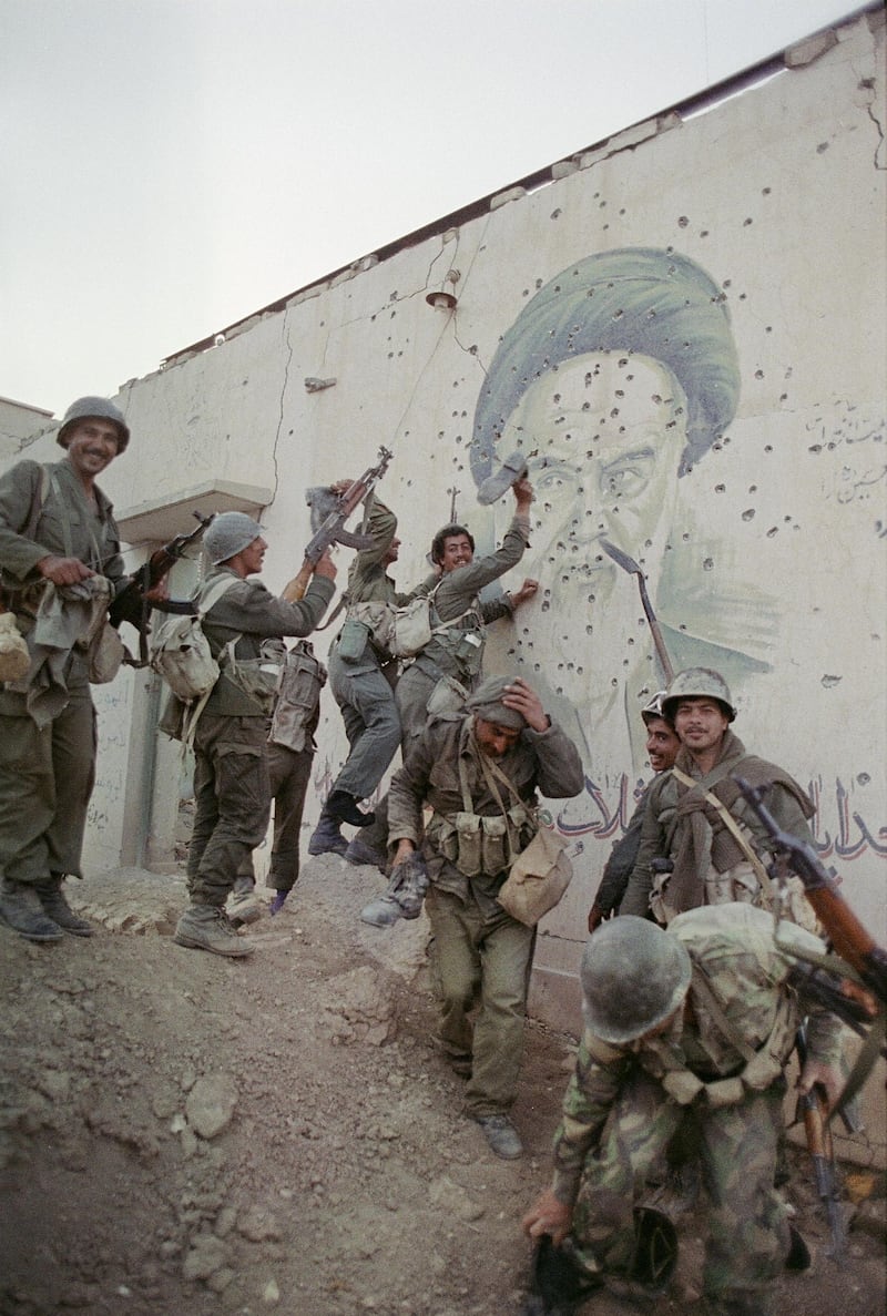 Iraqi soldiers pose in front of a  mural of Ayatollah Ruhollah Khomeini in the strategic Al Faw peninsula of southern Iraq on April 20, 1988. AFP