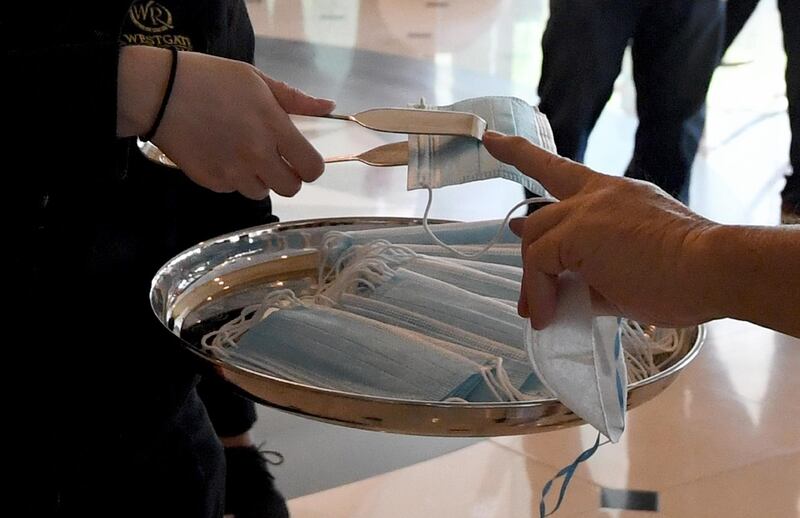 Tongs are used to give surgical masks to guests entering the Westgate Las Vegas Resort & Casino after the property opened for the first time since being closed in mid-March because of the coronavirus pandemic on June 18, 2020 in Las Vegas, Nevada, USA. AFP