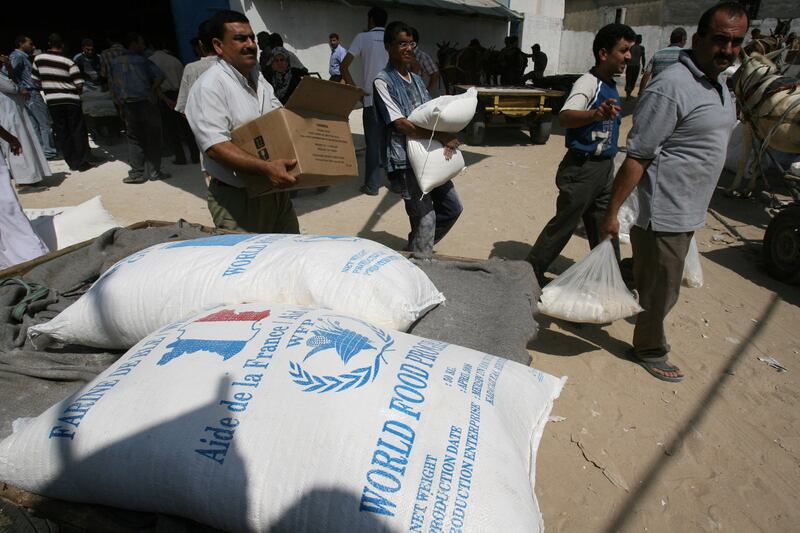 Palestinians carry food aid distributed by the United Nations Relief and Works Agency at Al-Shati refugee camp in Gaza, in September 2008. AFP