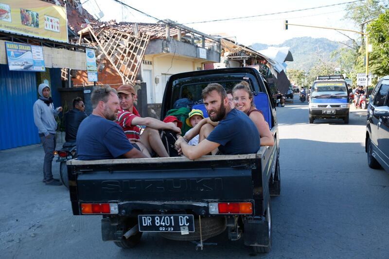 Foreign tourists ride in the back of a vehicle as they move to safer areas.  EPA