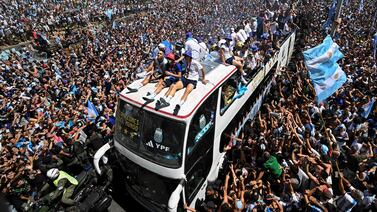 Fans of Argentina cheer as the team parades on board a bus after winning the Qatar 2022 World Cup tournament in Buenos Aires, Argentina on December 20, 2022.  - Millions of ecstatic fans are expected to cheer on their heroes as Argentina's World Cup winners led by captain Lionel Messi began their open-top bus parade of the capital Buenos Aires on Tuesday following their sensational victory over France.  (Photo by Luis ROBAYO  /  AFP)