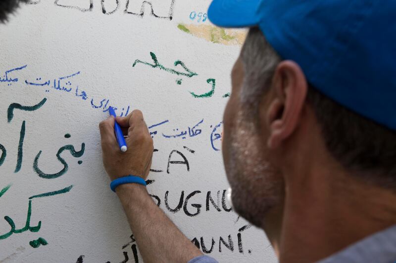 Khaled Hosseini writes a poem on the walls of of the Orient experience restaurant. ; UNHCR Goodwill Ambassador Khaled Hosseini meets refugees on the Italian island of Sicily. UNHCR/Andy Hall