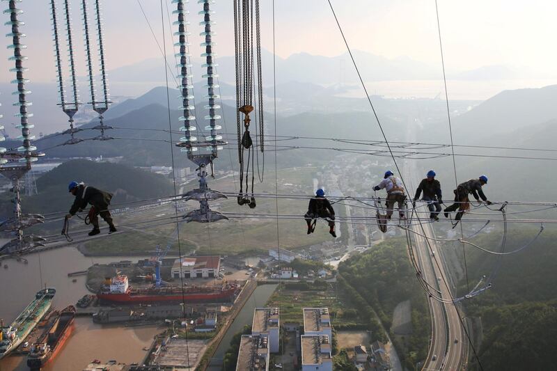 Men work on cables connecting power transmission towers in Zhoushan, Zhejiang province, China. Reuters