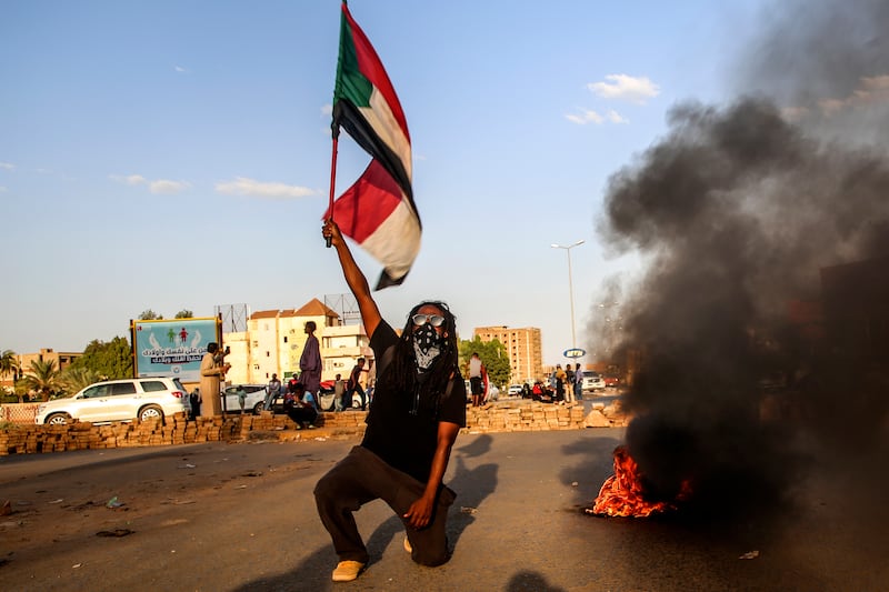 A Sudanese protester holds a national flag as thousands of people march during nationwide demonstrations following the military takeover. EPA / STR