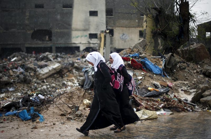 Palestinian schoolgirl walk past the rubble of a house that witnesses said was destroyed by Israeli shelling during a 50-day war in 2014 summer, on a rainy day in Beit Hanoun town in the northern Gaza Strip April 12, 2015. Suhaib Salem/Reuters