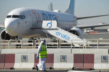 A mask-clad employee walks across a Flydubai aircraft on the tarmac of Dubai International Airport, on April 6, 2020. / AFP / KARIM SAHIB