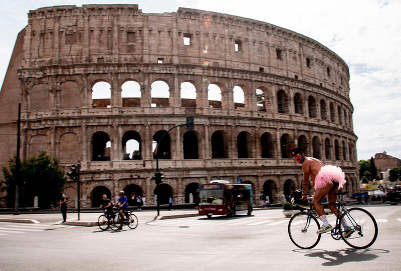 A man wearing a pink tutu rides a bicycle past the Coliseum monument as he takes part in a "Rome Pride LGBTI" flashmob in Rome, as the country eases its lockdown.   AFP