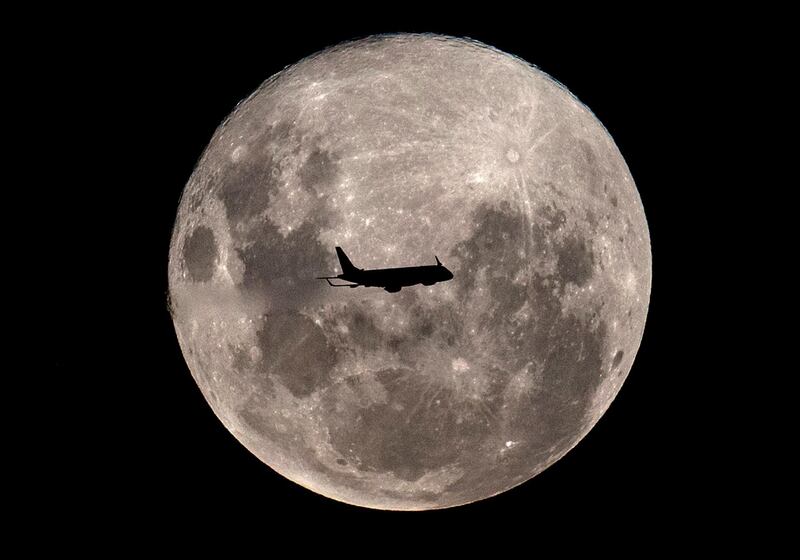 An Embraer 190-100IGW plane (registration LV-CKZ) of Aerolineas Argentinas, on a regular flight from Buenos Aires to the Argentine city of Bahia Blanca, passes in front of the "Supermoon" as seen from Buenos Aires on February 19, 2019.  / AFP / Alejandro PAGNI
