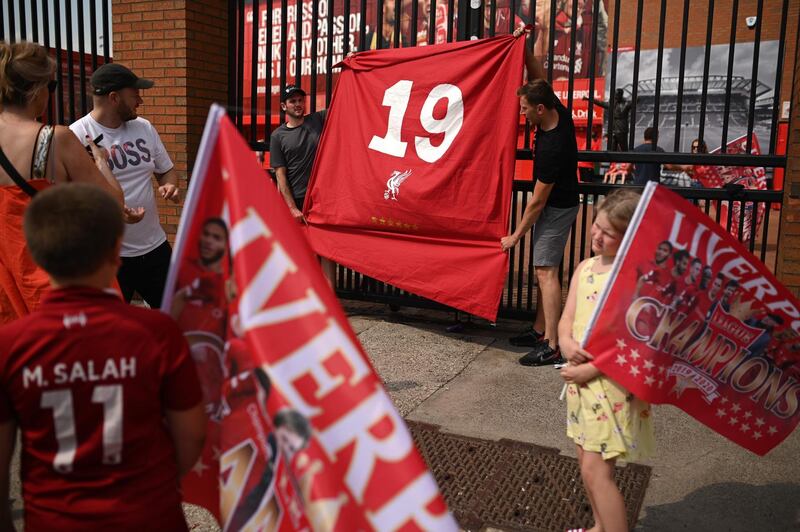 Liverpool fans hold a flag with the No 19 for their 19th league title  outside Anfield. AFP