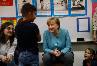 German Chancellor Angela Merkel, center, speaks with a Syrian displaced student during her visit to a Lebanese public school, where Lebanese and Syrian student studying together, in Beirut, Lebanon, Friday, June 22, 2018. Merkel is visiting Jordan and Lebanon, both neighbors of war-torn Syria, amid an escalating domestic row over migration. (AP Photo/Hussein Malla)