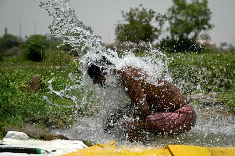 A man takes a shower in water pouring from a pipe in Delhi's Yamuna flood plains. Temperatures in the Indian capital have soared to a record high of 49.9°C. AFP