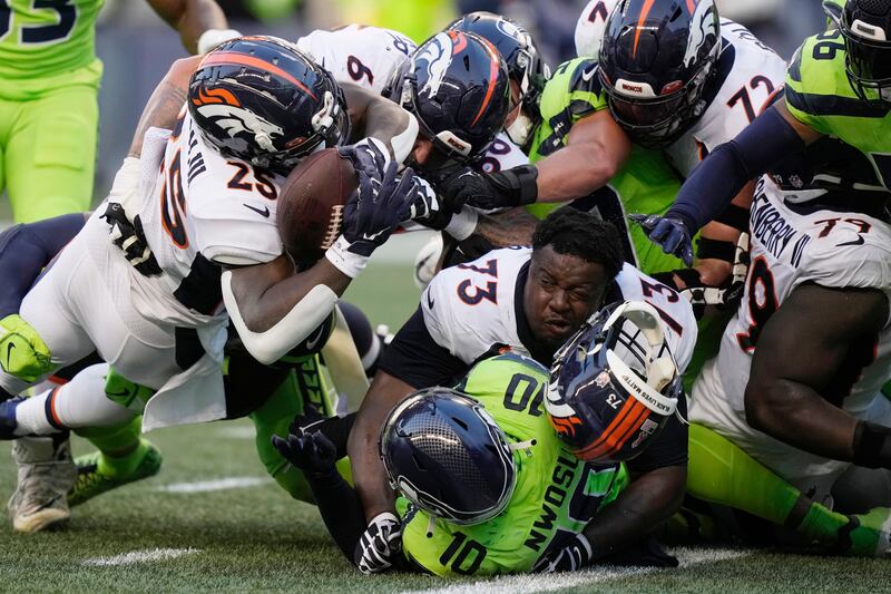 Denver Broncos' running back Melvin Gordon III, upper left, fumbles the ball as Broncos' offensive tackle Cameron Fleming (73) loses his helmet during an NFL football game against the Seattle Seahawks. AP