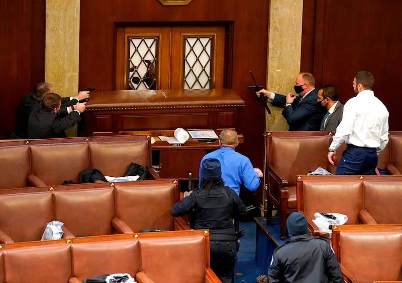 US Capitol police officers point their guns at a door that was vandalized in the House Chamber during a joint session of Congress. AFP
