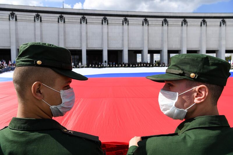 Russian servicemen wearing a face mask roll out a huge Russian national flag during a celebration ceremony of the National Flag Day at Poklonnaya Hill in Moscow.   AFP