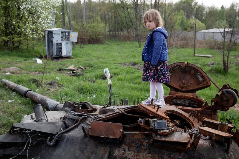 A child stands on a destroyed Russian tank near Makariv, Kyiv region. Reuters