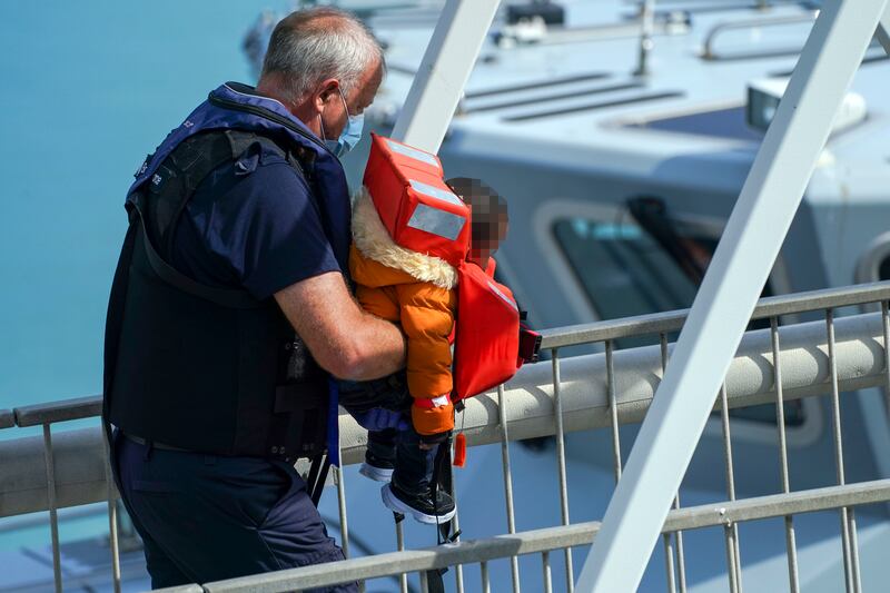 A young child is carried ashore as a group of people thought to be migrants are brought in to Dover, Kent, by Border Force officers. PA