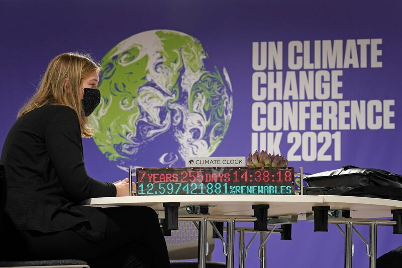 A delegate sits on a table that has an installation showing the 'Climate Clock'. AP Photo