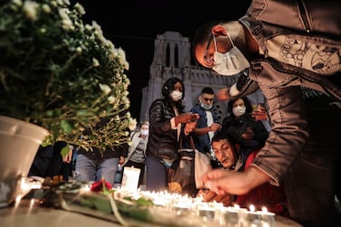 TOPSHOT - People lights candle outside the Notre-Dame de l'Assomption Basilica in Nice on October 29, 2020 in tribute to the three victims of a knife attacker, cutting the throat of at least one woman, inside the church of the French Riviera city. / AFP / Valery HACHE