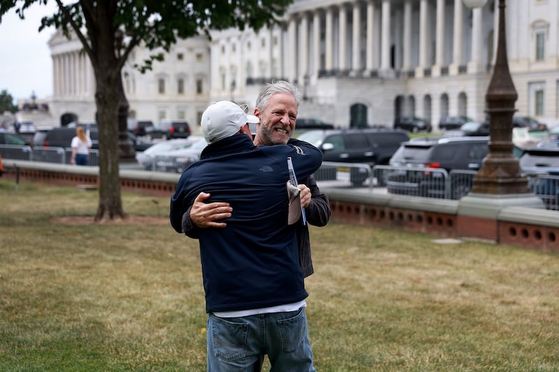 Stewart hugs 9/11 advocate John Feal.  Getty Images / AFP
