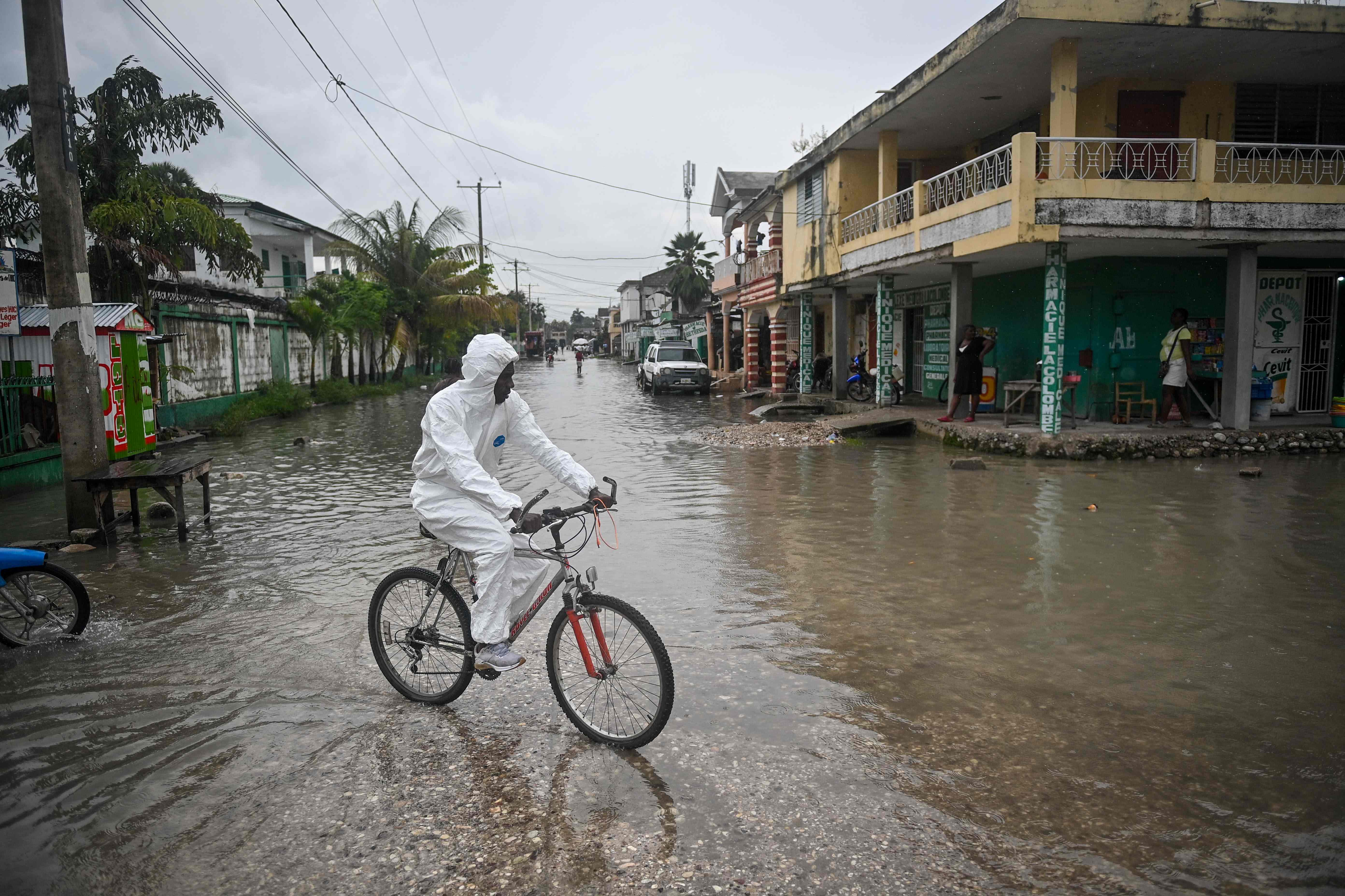 A man rides his bicycle through a flooded neighborhood in Les Cayes. AFP