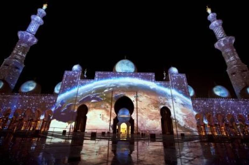 People enjoy a light show projected on the walls of the Sheikh Zayed Mosque on Tuesday evening, Nov. 29, 2011, in celebration of the upcoming 40th anniversary of the UAE creation at the mosque in Abu Dhabi. (Silvia Razgova/The National)
