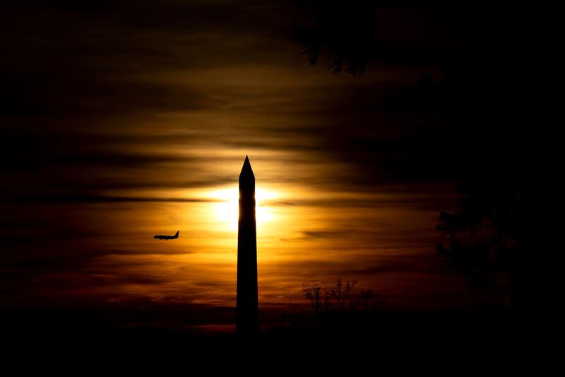 A plane flies past the Washington Monument in Washington, DC, at sunset. AFP