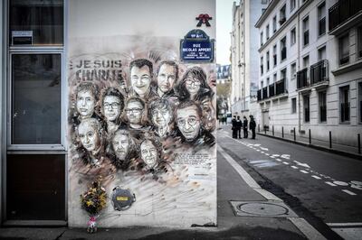 (FILES) In this file photo taken on January 07, 2019 Policemen are seen next to a painting by French street artist and painter Christian Guemy, known as C215, in tribute to members of Charlie Hebdo newspaper who were killed by jihadist gunmen in January 2015. Officers arrested the suspected attacker after four people were injured in a knife assault in Paris on September 25, 2020, near the former offices of satirical weekly Charlie Hebdo, French police said. The man was arrested near the sprawling Place de la Bastille, police said, adding he was the only suspect in an attack that came as a trial is under way for alleged accomplices in the January 2015 attack on Charlie Hebdo that killed 12 people.
 - RESTRICTED TO EDITORIAL USE - MANDATORY MENTION OF THE ARTIST UPON PUBLICATION - TO ILLUSTRATE THE EVENT AS SPECIFIED IN THE CAPTION
 / AFP / STEPHANE DE SAKUTIN / RESTRICTED TO EDITORIAL USE - MANDATORY MENTION OF THE ARTIST UPON PUBLICATION - TO ILLUSTRATE THE EVENT AS SPECIFIED IN THE CAPTION
