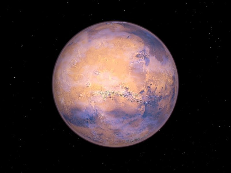 A full Mars. In this image the massive volcano Olympus Mons is clearly visible upper left of center, while at center are the three Tharsis Montes volcanoes. All these volcanoes are believed to be extinct. To the right of the Tharsis Montes are the deep canyons of Valles Marineris, a meandering network of channels as long as the United States is wide.  Mars has been known historically as a bright, reddish star in Earth's sky. The ruddy hue is due to the presence of iron oxide (i.e., rust) on the martian surface. Mars is often host to white clouds of water09/14/2009ice crystals (like the high09/14/2009altitude cirrus clouds on Earth) and experiences seasonal dust storms that can cover the entire planet.