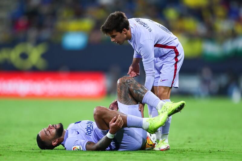 Memphis Depay is helped by Barcelona teammate Ricard Puig after falling to the pitch. Getty Images