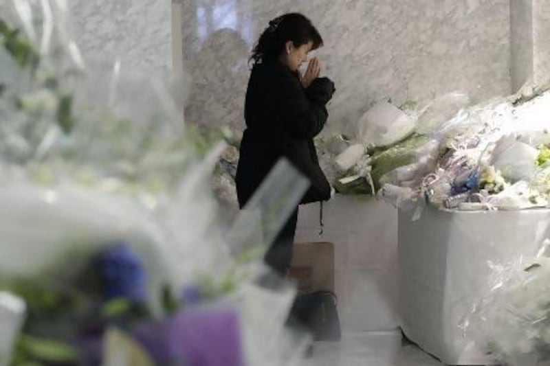 A woman prays near bouquets left at the company’s Yokohama headquarters to honour the Japanese employees of JGC Corporation who died in the standoff at the Ain Amenas gas plant in Algeria.