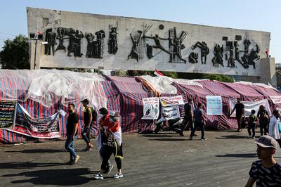 Iraqi protesters walk past sit-in tents erected at an anti-government demonstration in the capital Baghdad's Tahrir Square on November 6, 2019.  / AFP / SABAH ARAR

