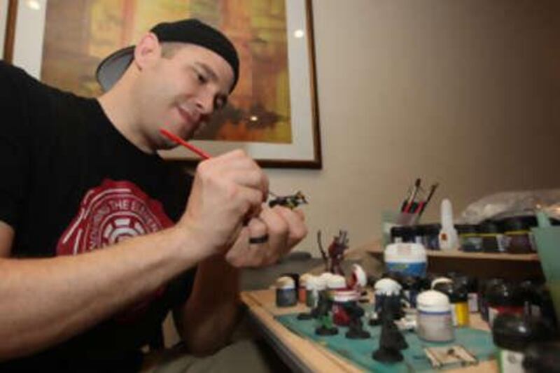 Trevor Van Cleave paints his collection of Warhammer warrior figurines at his house in Dubai.