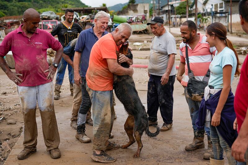 A man is reunited with his dog, which was rescued from the mud by neighbours after flooding  in Las Tejerias, Venezuela. AP Photo